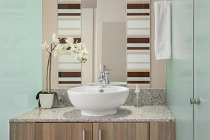 A bathroom with a white sink, a potted orchid, and a towel hanging on the wall. - Easy Stay - The Tyrwhitt (Johannesburg)