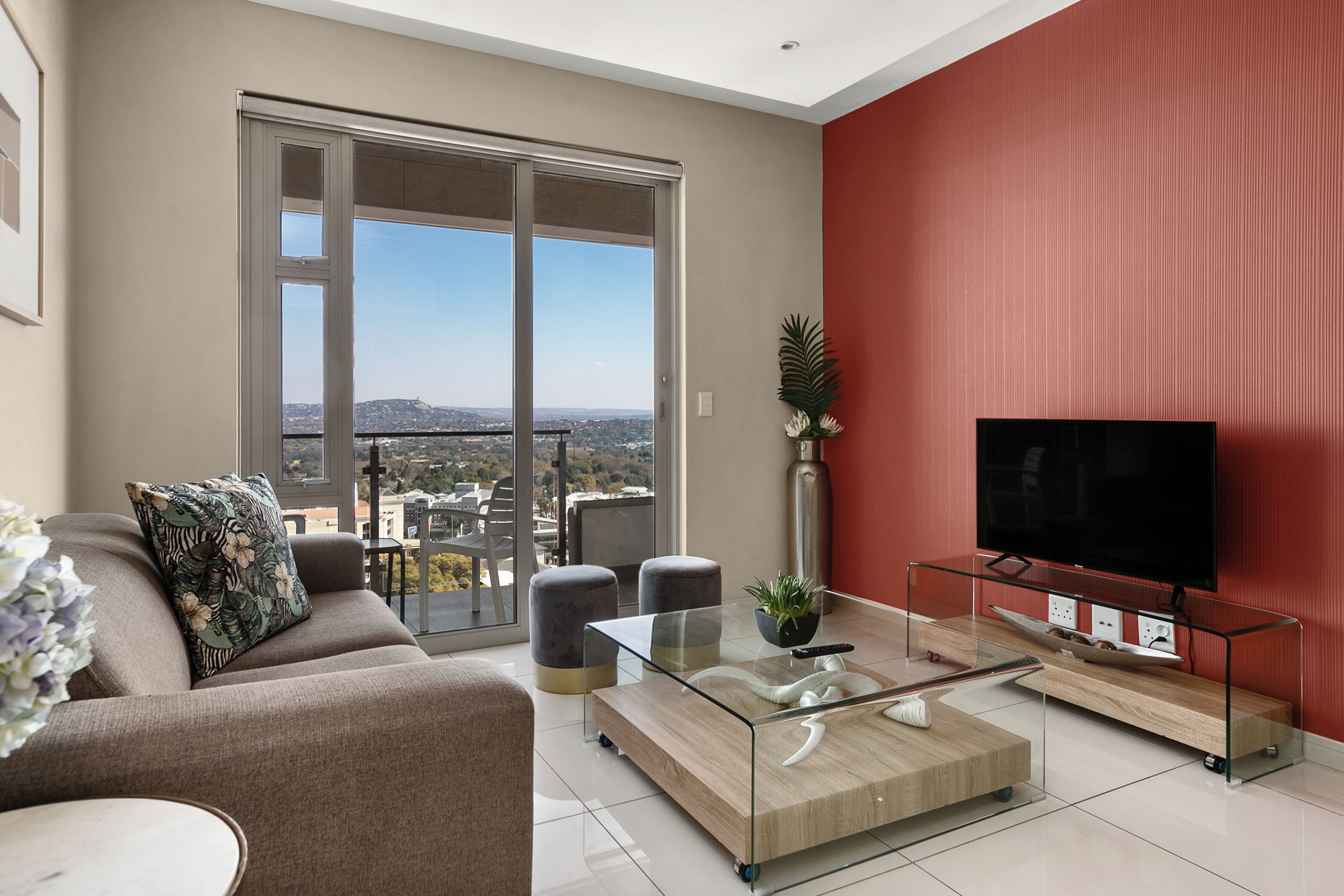 A modern living room with a large sliding glass door, a flat-screen TV, and a minimalist coffee table.