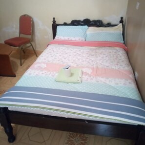 A bed with a floral bedspread, a pillow, and a folded towel on it. - Harvester Restaurant (Nakuru)
