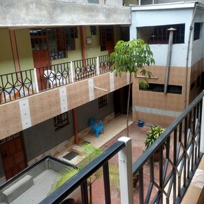 A multi-level building with a balcony, a blue plastic chair, and potted plants. - Harvester Restaurant (Nakuru)