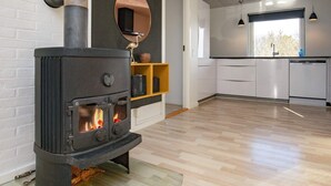 Et moderne køkken med brændeovn, stort vindue og minimalistisk indretning.