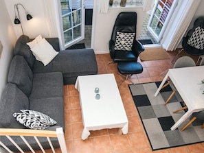 A modern living room with a grey sofa, a black leather chair, a white coffee table, and a dining table with chairs. - 5 Star Holiday Home in Blavand (Blavand)