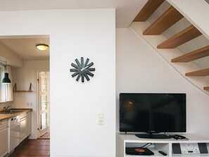 A modern living room with a flat-screen TV, a decorative wall clock, and a staircase. - 5 Star Holiday Home in Blavand (Blavand)