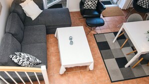 A modern living room with a grey sofa, a black leather chair, a white coffee table, and a dining table with chairs. - 5 Star Holiday Home in Blavand (Blavand)