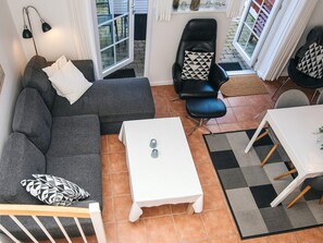 A modern living room with a grey sofa, a black leather chair, a white coffee table, and a dining table with chairs. - 5 Star Holiday Home in Blavand (Blavand)