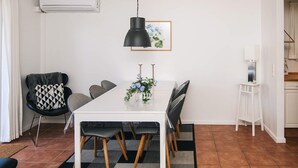 A dining area with a white table, black chairs, a black pendant light, and a framed picture on the wall. - 5 Star Holiday Home in Blavand (Blavand)