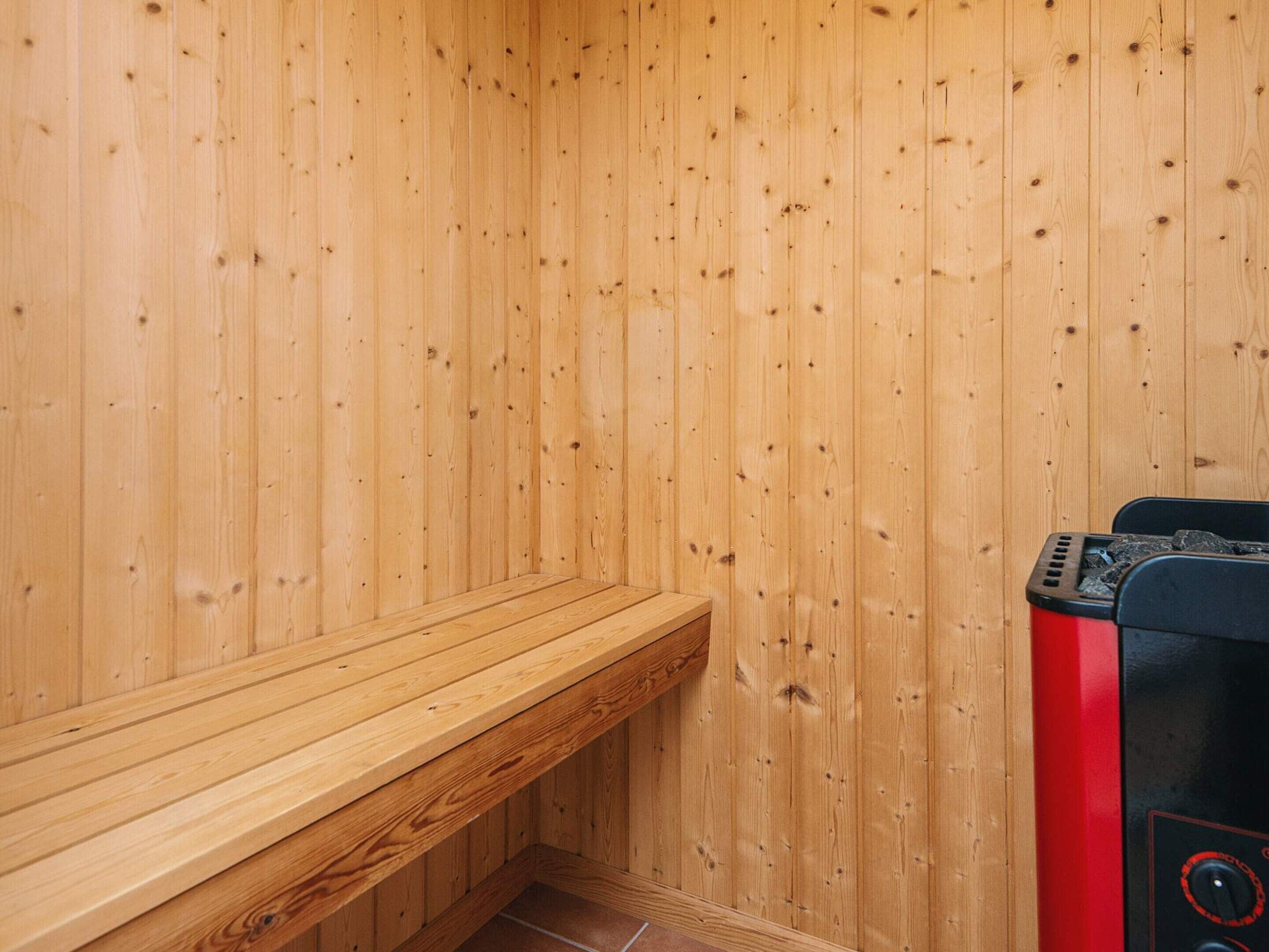 A sauna room with wooden walls and a bench.