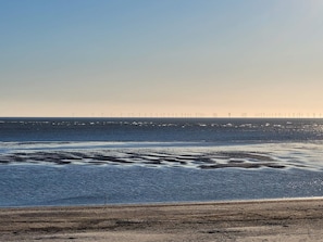 A beach with waves and wind turbines in the distance. - 5 Star Holiday Home in Blavand (Blavand)