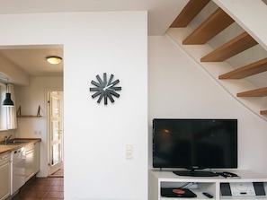 A modern living room with a flat-screen TV, a decorative wall clock, and a staircase. - 5 Star Holiday Home in Blavand (Blavand)