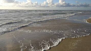 A beach with waves and a clear sky.