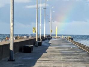 Une jetée dotée de lampadaires et de panneaux d’avertissement, qui mène à la mer.