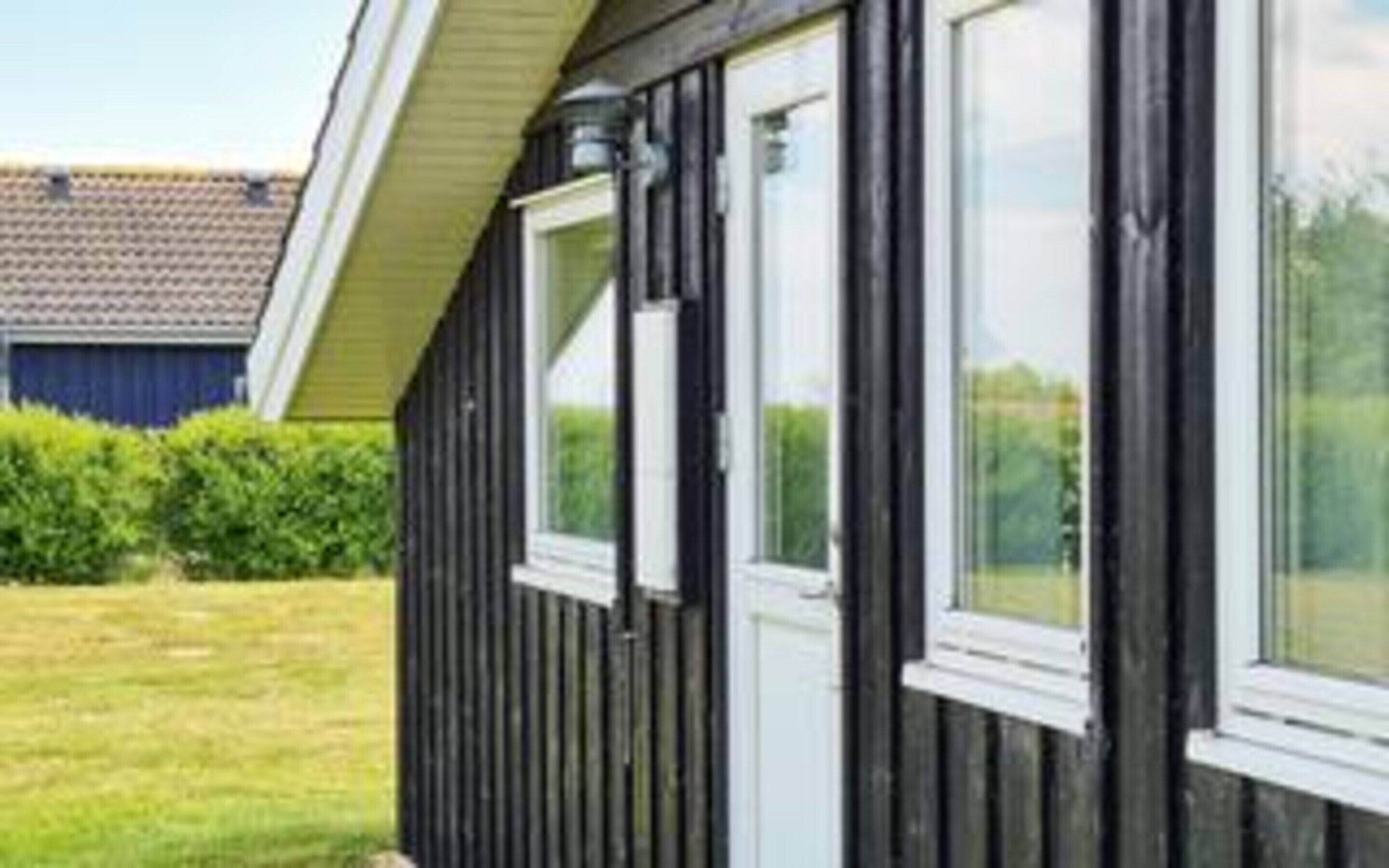 Een zwart gebouw met ramen voorzien van witte kozijnen en een schuin dak.