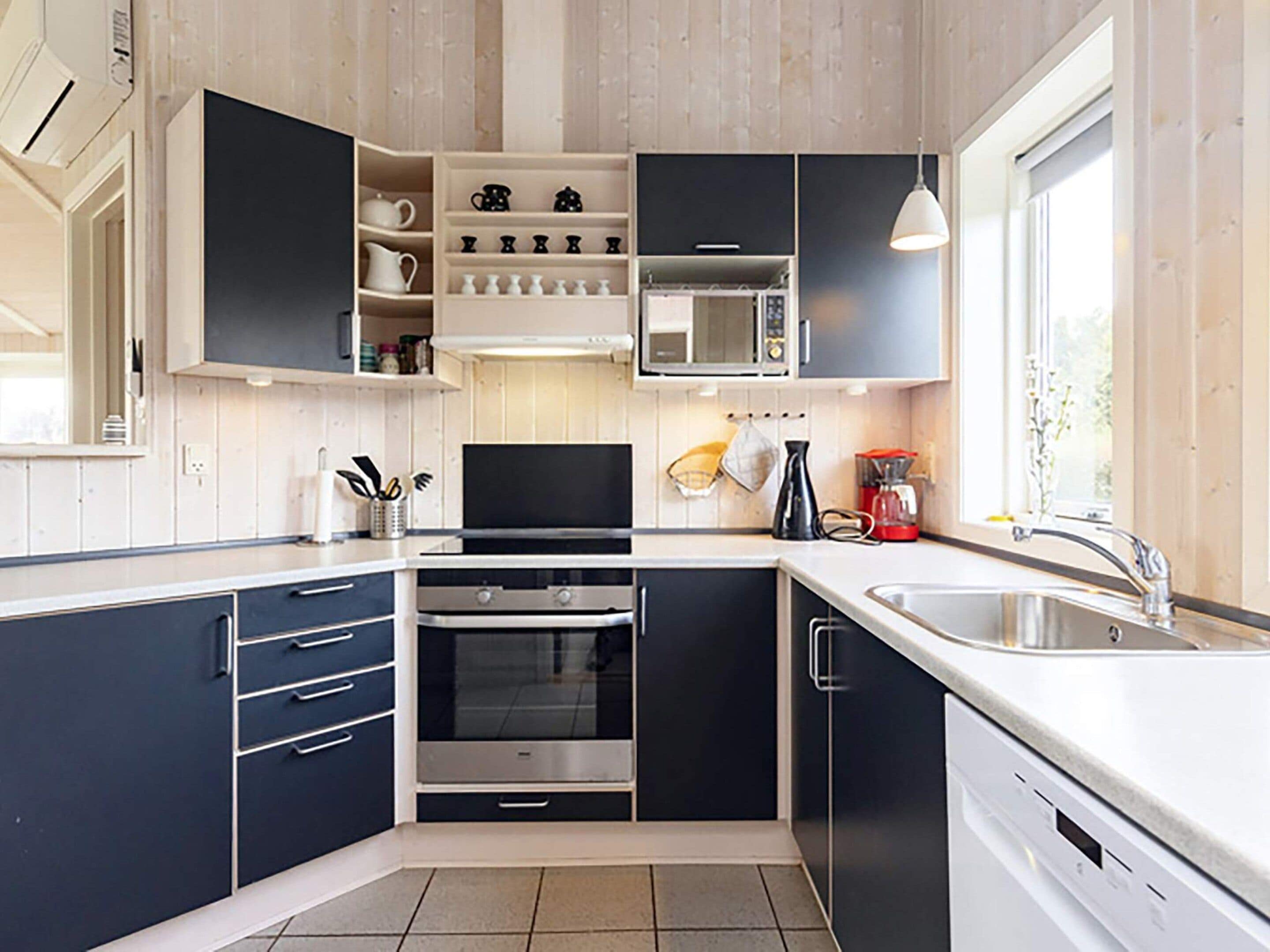 A modern kitchen with built-in appliances, a large window, and a sink.