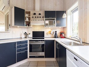 A modern kitchen with built-in appliances, a large window, and a sink. - 4 Star Holiday Home in Rudkobing (Rudkobing)