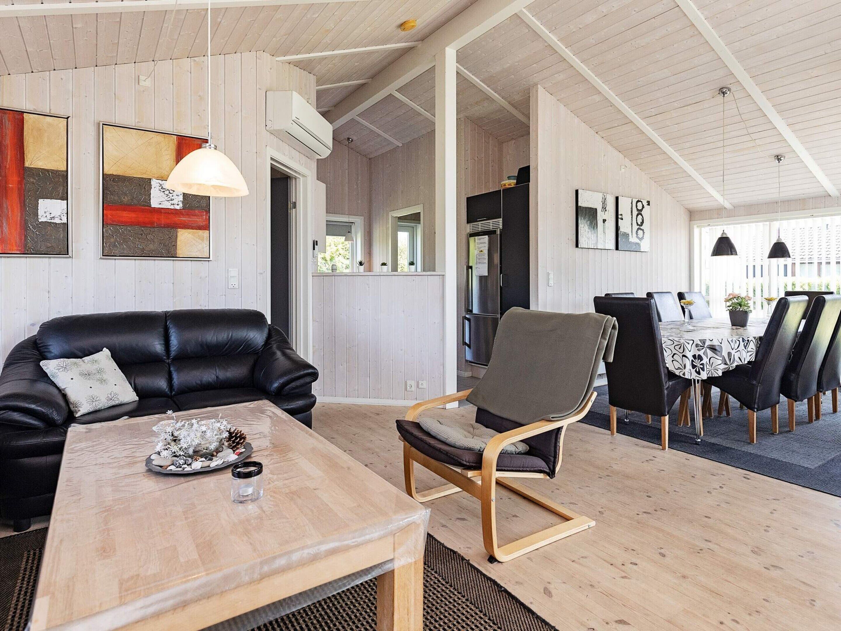 A modern interior with a leather sofa, a wooden table, and a dining area with chairs.