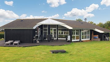 A modern house with a covered patio, a deck, and a large windowed area.