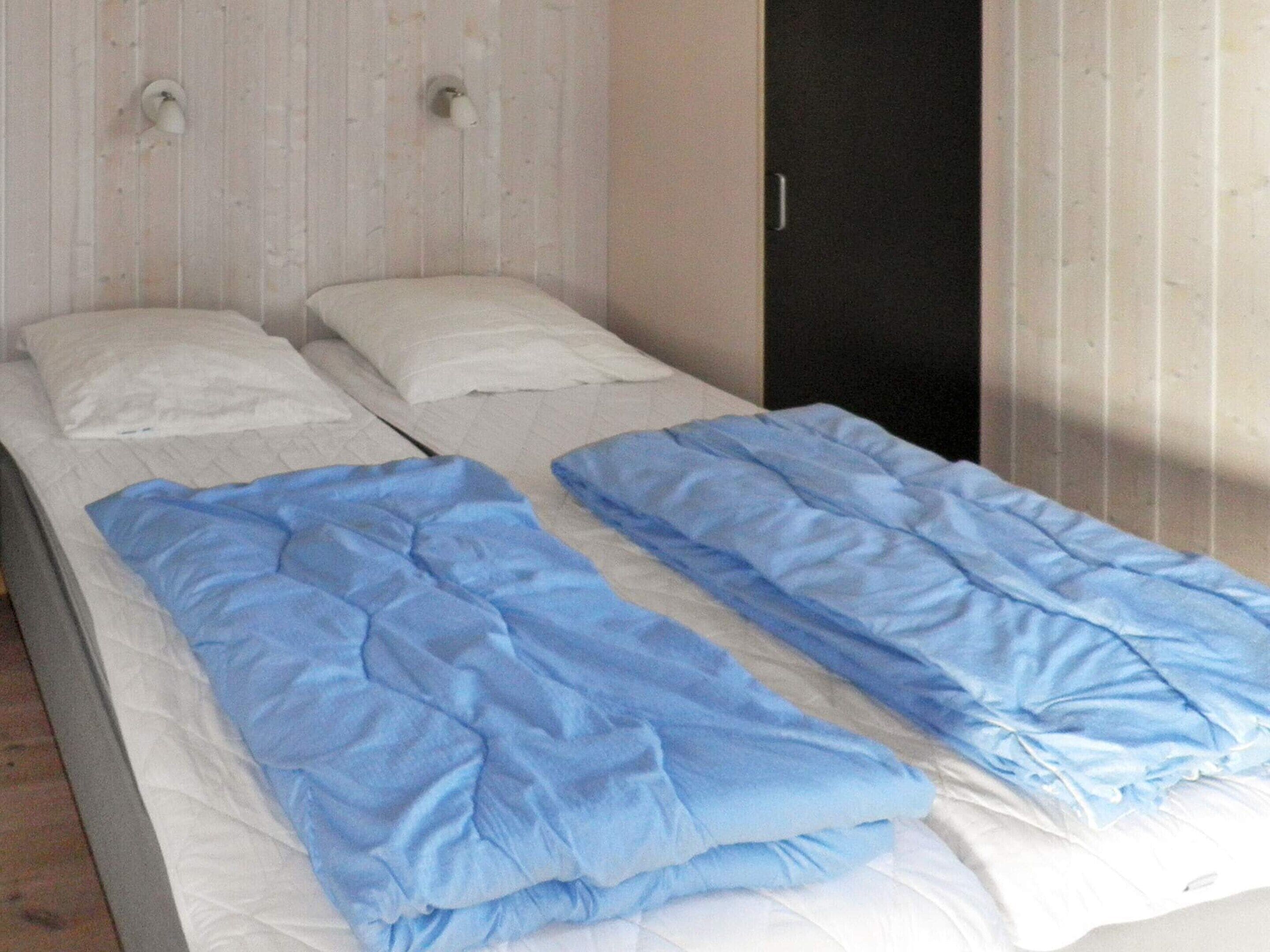 Un lit simple avec un matelas blanc et une literie bleue.