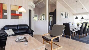 A modern interior with a wooden dining table, a leather sofa, and a wooden rocking chair.