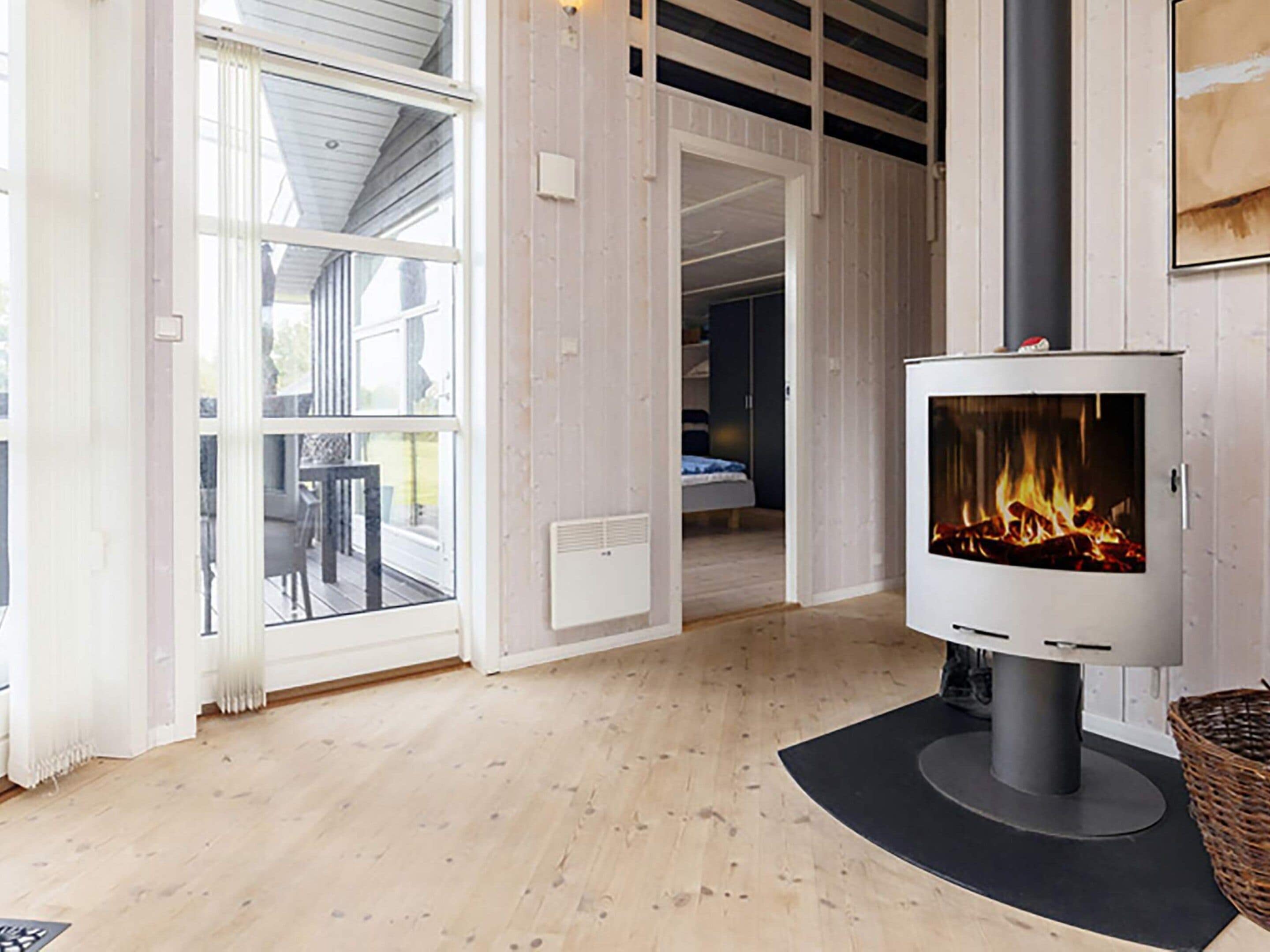 A room with a fireplace, a door leading to a balcony, and a bed in the background.