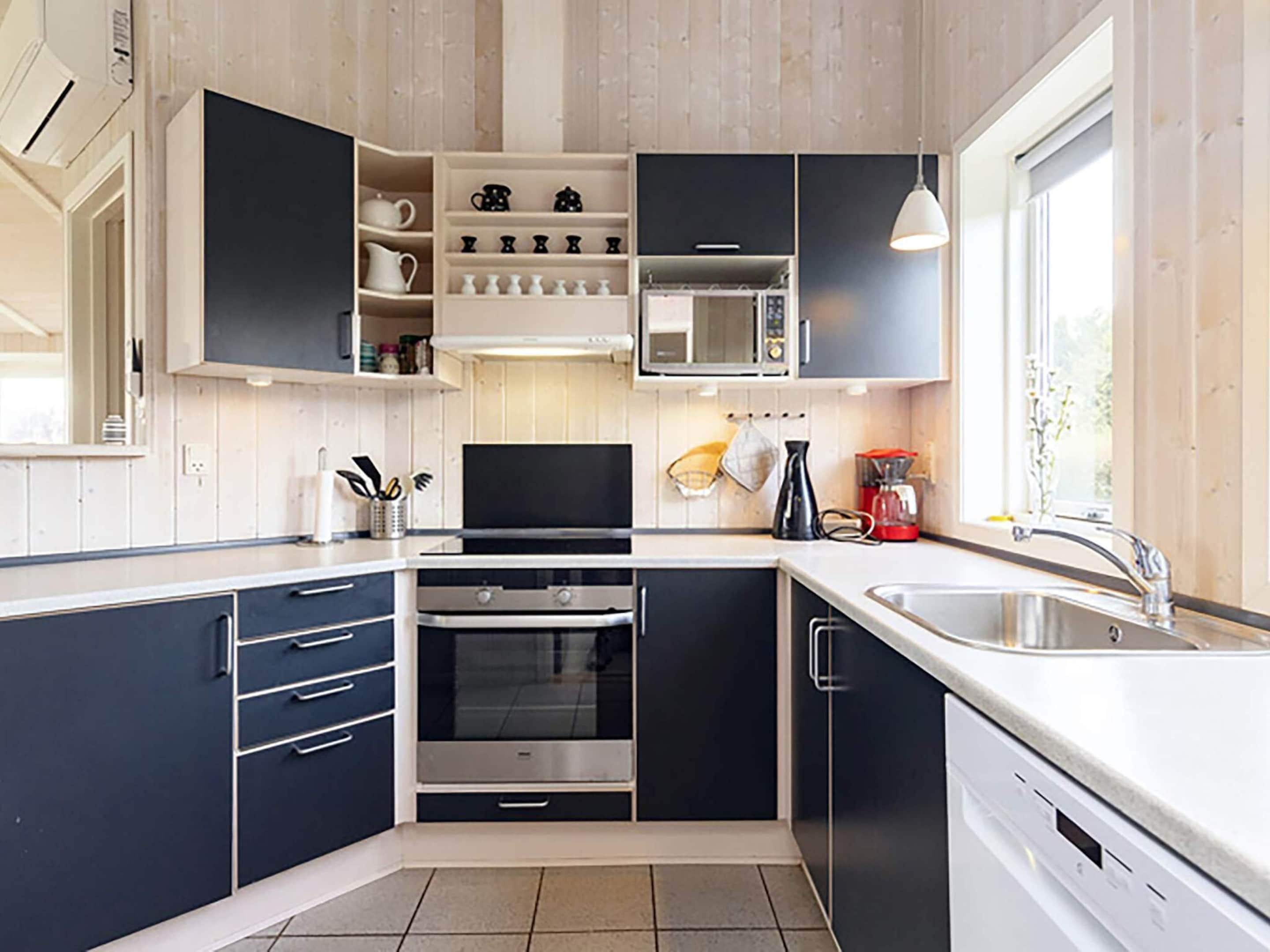 A modern kitchen with built-in appliances, a large window, and a view of the outdoors.