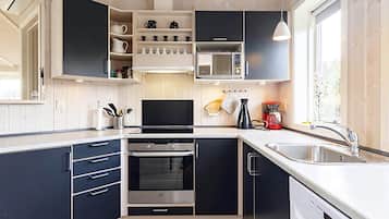 A modern kitchen with built-in appliances, a large window, and a view of the outdoors.