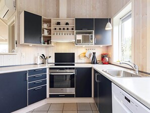 A modern kitchen with built-in appliances, a large window, and a view of the outdoors.
