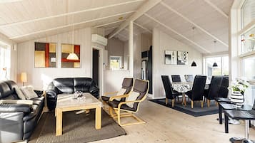 A spacious living area with a high ceiling, a dining table with chairs, and a sofa.
