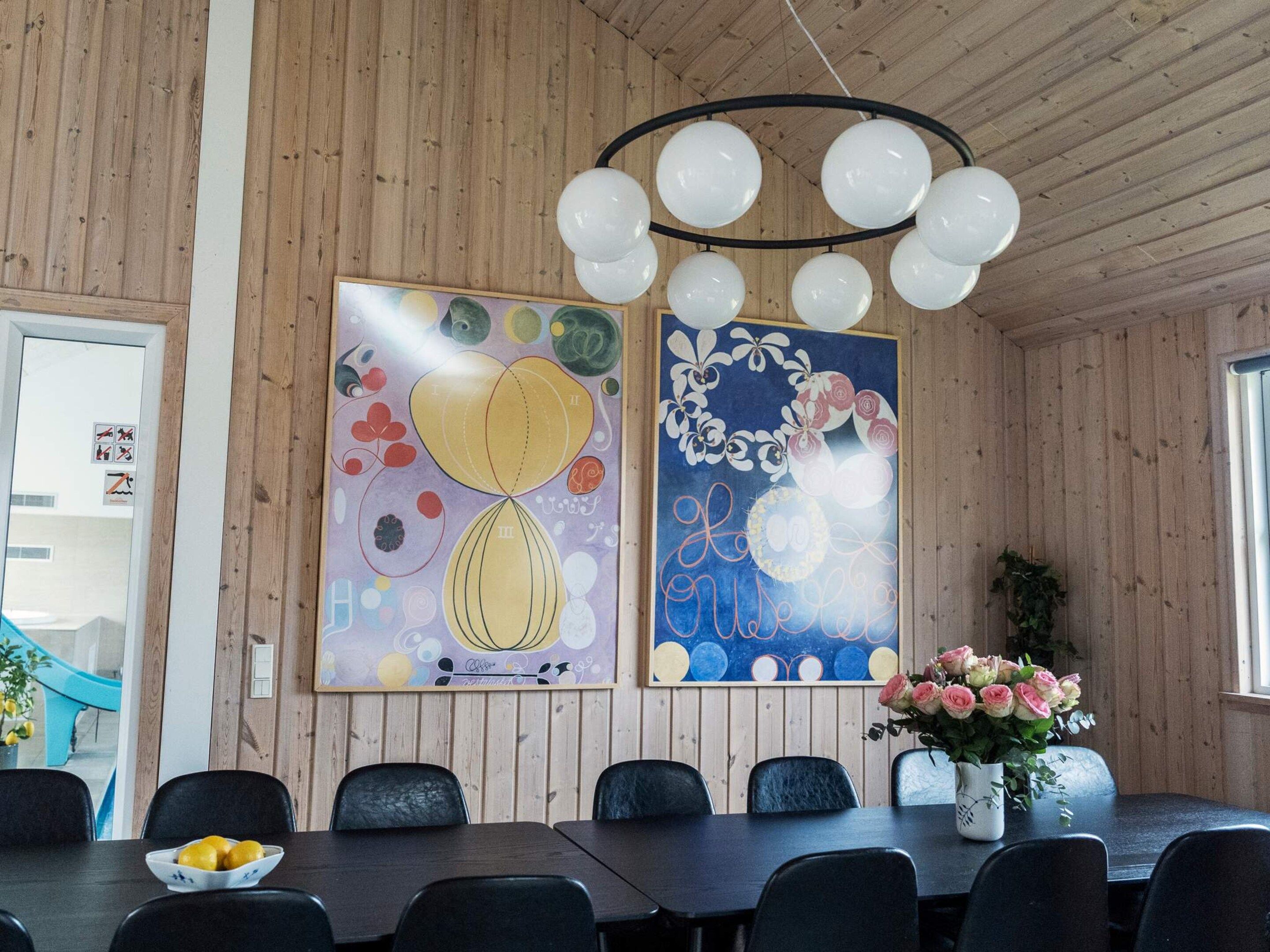 Een eetgedeelte met een lange tafel, zwarte stoelen en een bloevas.