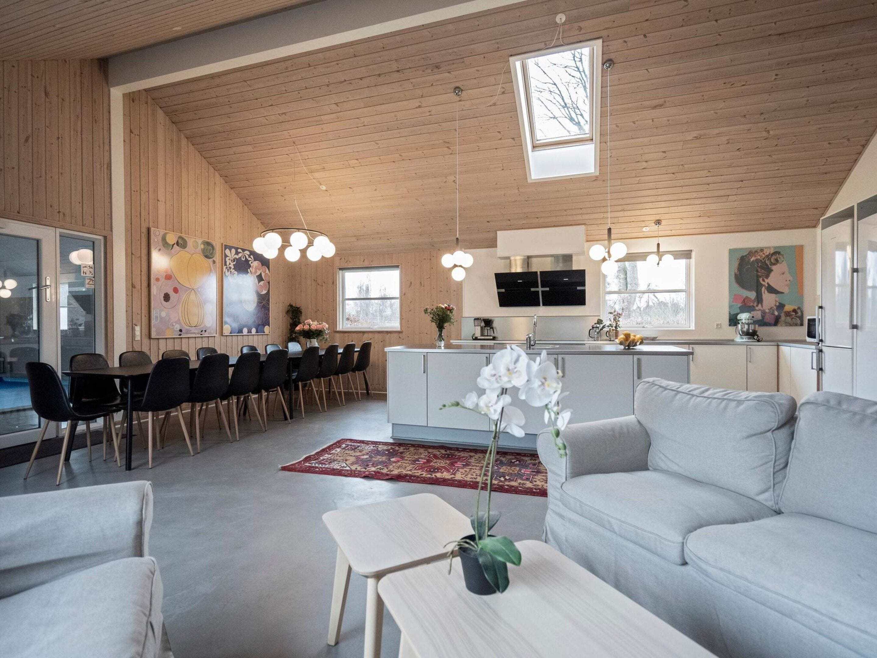 A spacious living area with a dining table, sofas, and a kitchen in the background.