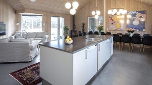 A modern kitchen with a central island, a dining area with chairs, and a living room with a sofa.