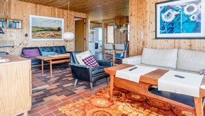 Un intérieur en bois comprenant un canapé, des fauteuils, une table et un tapis.
