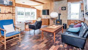 Un intérieur de chalet chaleureux avec des murs en bois, une cheminée, un téléviseur et un coin repas.