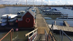 A marina with boats docked, a wooden pier, and a small red building with a lifebuoy. - Serene Holiday Home in Fanø near Restaurants (Fano)