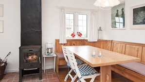A cozy room with a wooden table, benches, a fireplace, and a window with curtains. - Serene Holiday Home in Fanø near Restaurants (Fano)