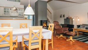 Amplia sala de estar con mesa de comedor, sillas, chimenea y sofá de cuero.