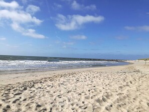 A sandy beach with waves, a clear sky, and a rocky breakwater in the distance. - 4 Star Holiday Home in Blavand (Blavand)