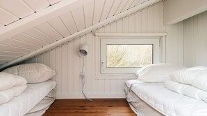 A bedroom with two beds, wooden flooring, a window with a view of trees, and a ceiling fan. - Cozy Holiday Home in Fanø near Beach (Fano)