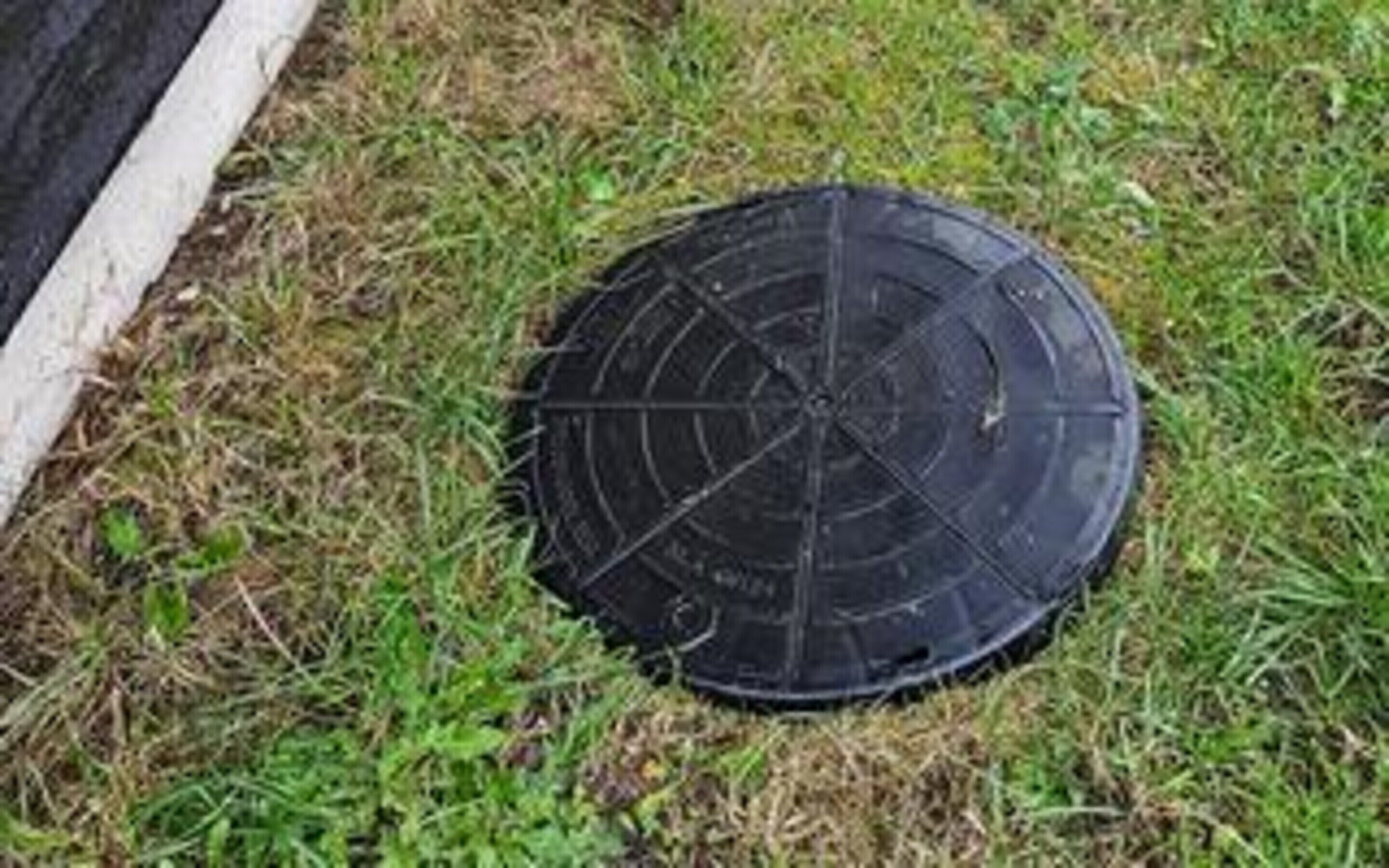 A manhole cover on grass.