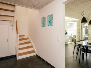 A staircase with wooden steps leading to a landing, a dining area with a table and chairs, and two wall-mounted maps.