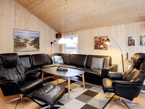 A modern living room with a leather sofa, a coffee table, and a black leather chair.
