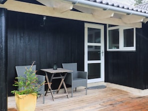 A patio with a table and two chairs, a potted plant, and a sliding glass door. - 4 Star Holiday Home in Lokken (Lokken)