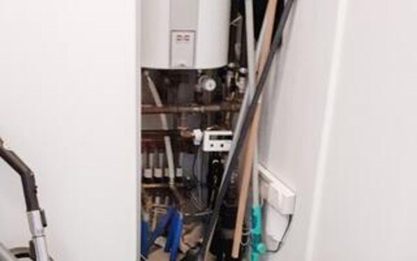 A narrow hallway with a water heater, pipes, and a control panel.