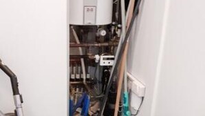 Quarto com aquecedor de água, tubulações e painel de controle visíveis.