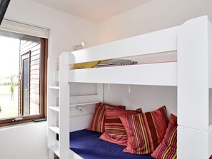 Una cama litera con ventanal, una puerta blanca y vistas al exterior.