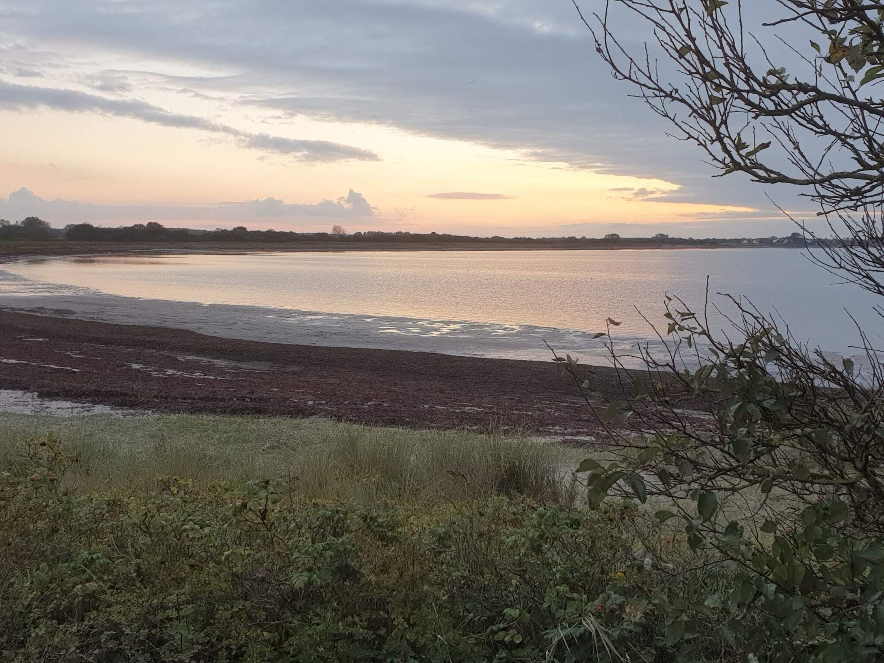 Une rive de rivière d’où l’on peut admirer l’eau et le ciel.