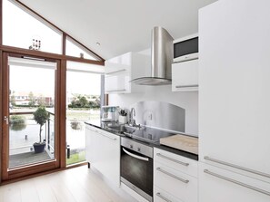 A modern kitchen with a large window, stainless steel appliances, and a view of a courtyard.