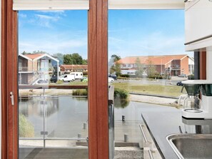 A view through a window with a clear sky, a body of water, and buildings in the background.