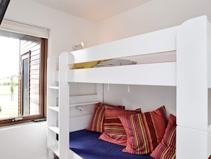A bunk bed with a window, a white wall, and a door.