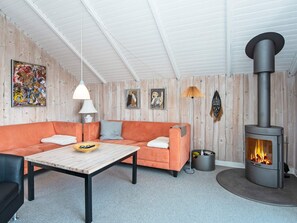 A cozy living room with a sofa, a coffee table, and a wood-burning stove.
