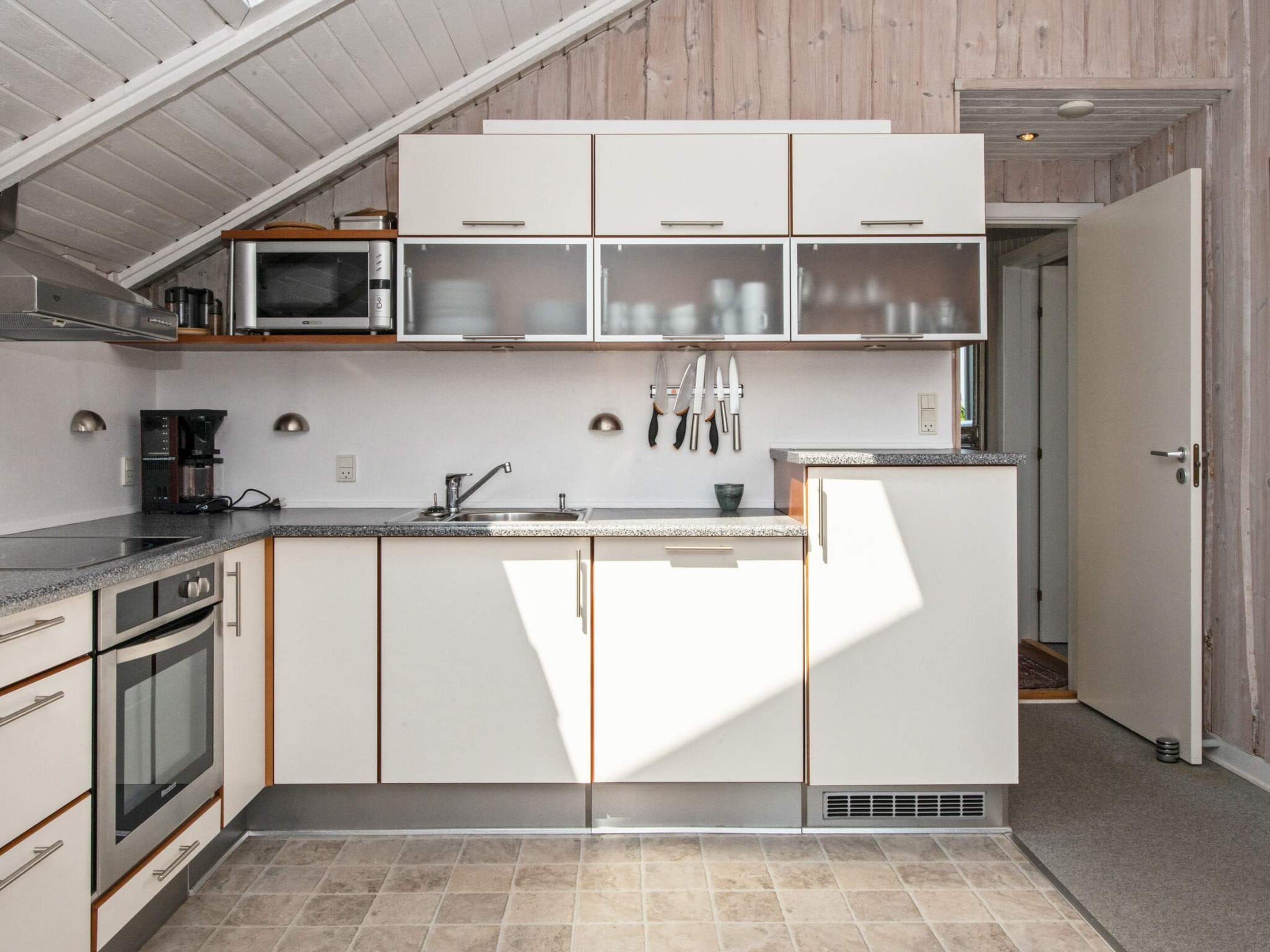 Een moderne keuken met witte kasten, een magnetron, een koffiezetapparaat en een spoelbak.